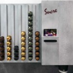 Vue face avant du distributeur de dosettes avec compartiments sucre, touillettes et gobelets. Face avant du distributeur de dosette Nespresso de LaserEnFolie